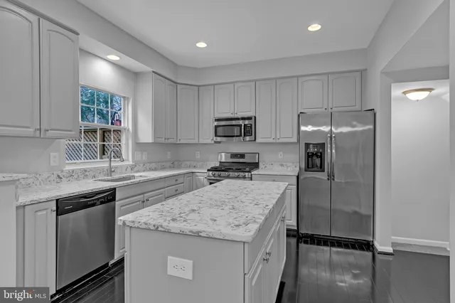 a kitchen with a refrigerator a microwave a sink and cabinets