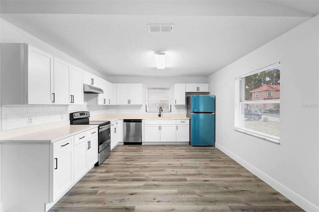 860 South Grove Street Eustis, FL 32726 - Photo 47 of 54 a kitchen with white cabinets and wooden floor