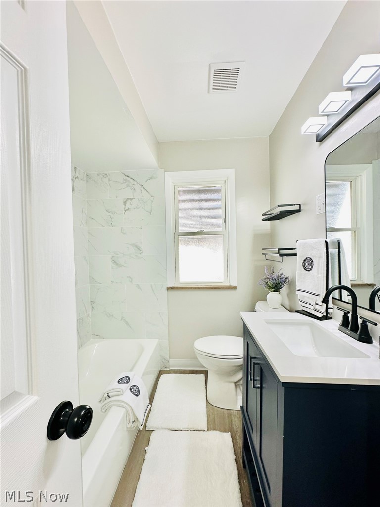 7607 Ridgefield Avenue Cleveland, OH 44129 - Photo 8 of 28 Full bathroom with tiled shower / bath, hardwood / wood-style flooring, toilet, and vanity