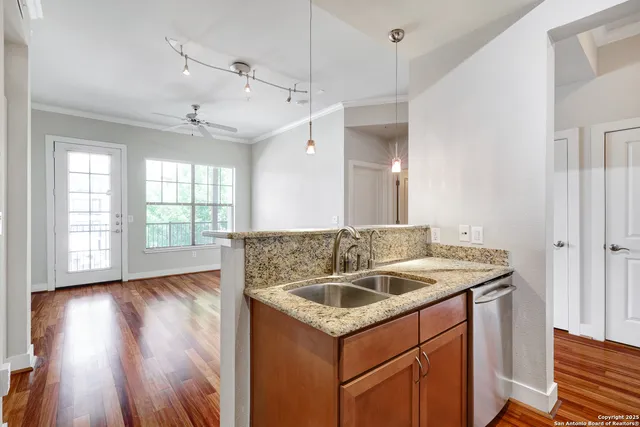 a kitchen that has a sink a window and wooden floor