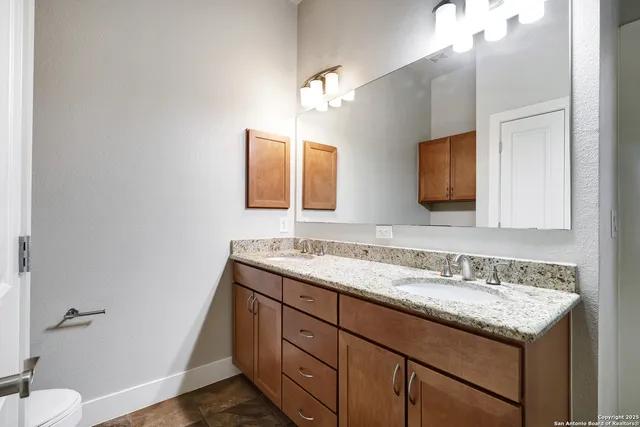 a bathroom with a granite countertop sink a large mirror and a toilet