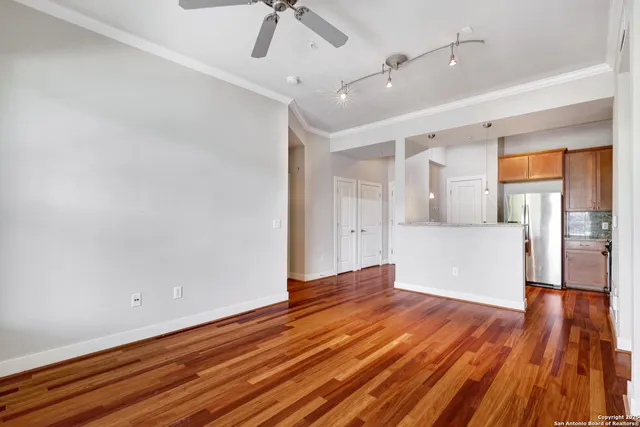 a view of empty room with wooden floor and fan
