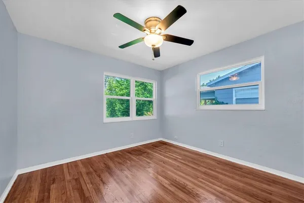 a view of empty room with wooden floor and fan