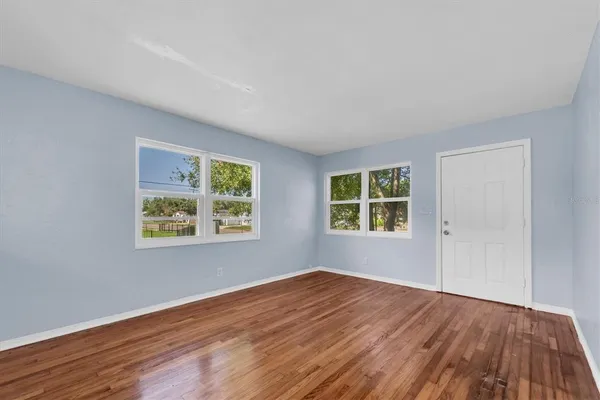 a view of empty room with wooden floor and fan