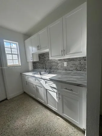 a kitchen with granite countertop white cabinets stainless steel appliances a sink and a window