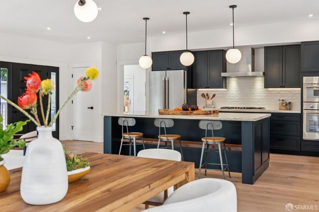 a kitchen with stainless steel appliances granite countertop a stove a kitchen island a dining table and chairs with wooden floor