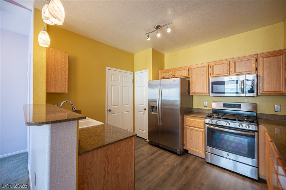 10550 West Alexander Road, Unit 2014 Las Vegas, NV 89129 - Photo 16 of 43 Warm wood cabinetry and granite countertops anchor this functional cooking space with durable vinyl flooring.