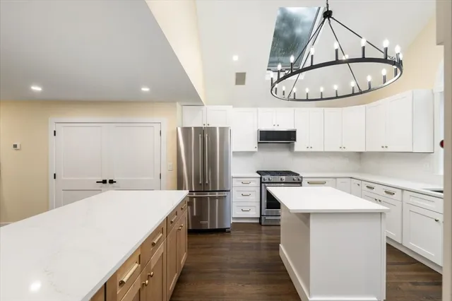 a kitchen with stainless steel appliances a refrigerator a sink a stove and white cabinets