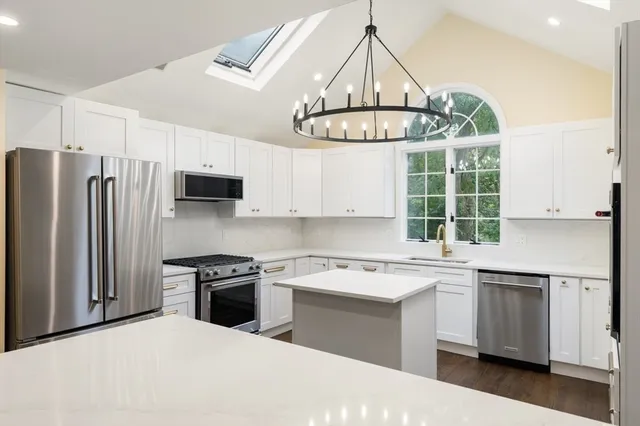 a kitchen with stainless steel appliances a sink a stove a refrigerator cabinets and a window