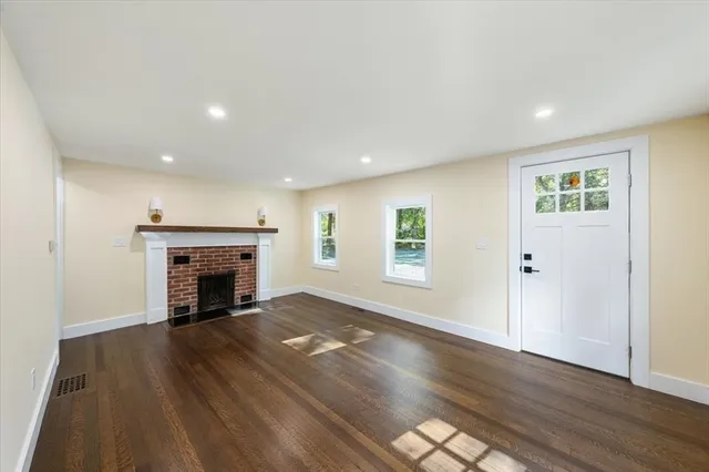 an empty room with wooden floor fireplace and windows