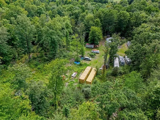 an aerial view of residential house with outdoor space and trees all around