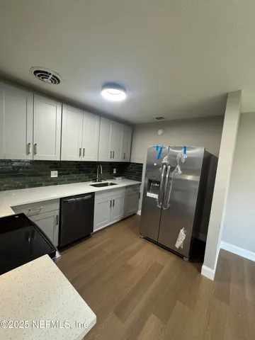 a kitchen with stainless steel appliances kitchen island granite countertop a sink a stove top oven and white cabinets