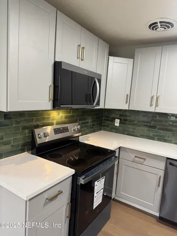 a kitchen with a sink dishwasher a stove and white cabinets