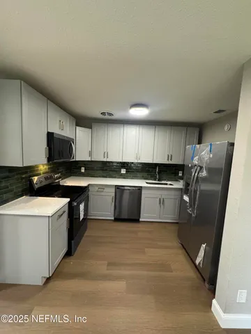 a kitchen with stainless steel appliances granite countertop a stove top oven a sink and a refrigerator