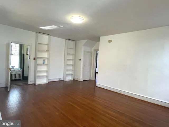 a view of an empty room with wooden floor and closet