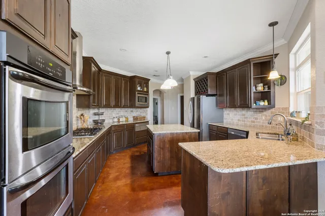 a kitchen with stainless steel appliances granite countertop a sink a stove and a refrigerator