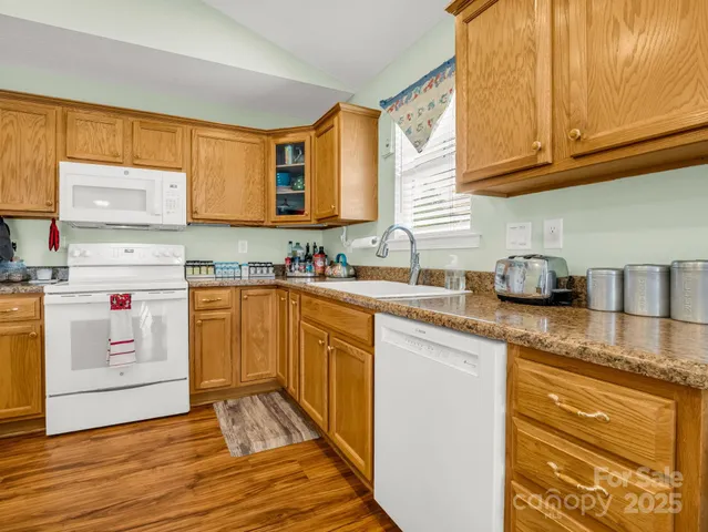 a kitchen with granite countertop a sink cabinets stainless steel appliances and a window