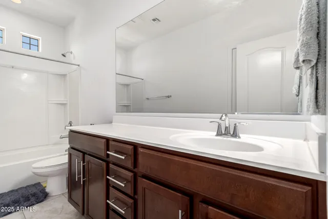 a bathroom with a granite countertop sink a toilet and a mirror