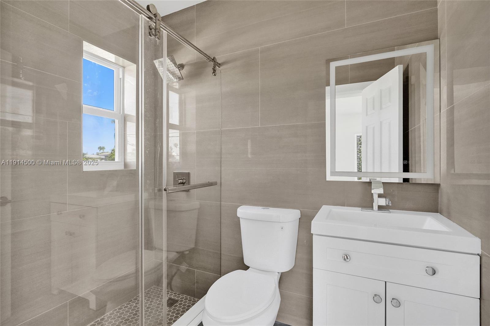 7115 Rue Granville, Unit C Miami Beach, FL 33141 - Photo 24 of 25 a bathroom with a toilet sink vanity and shower