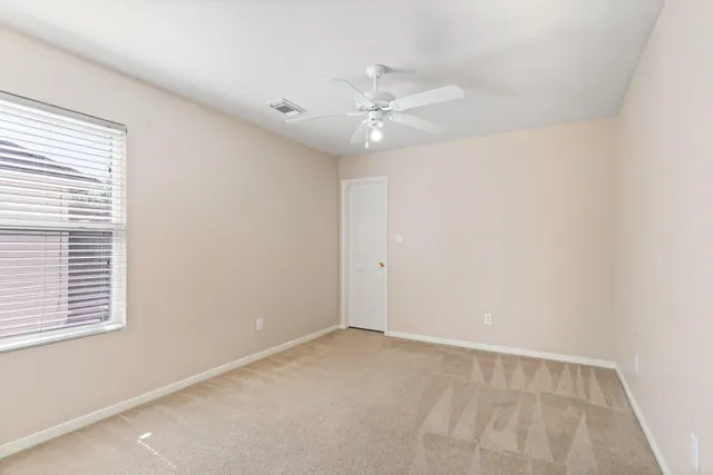 an empty room with a window and a ceiling fan