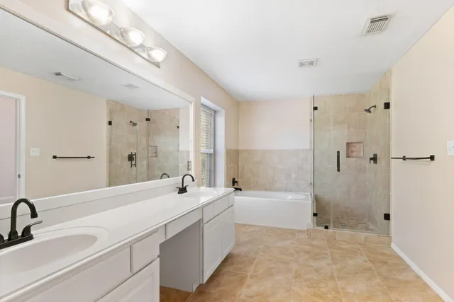 a bathroom with a double vanity sink a mirror and a bathtub