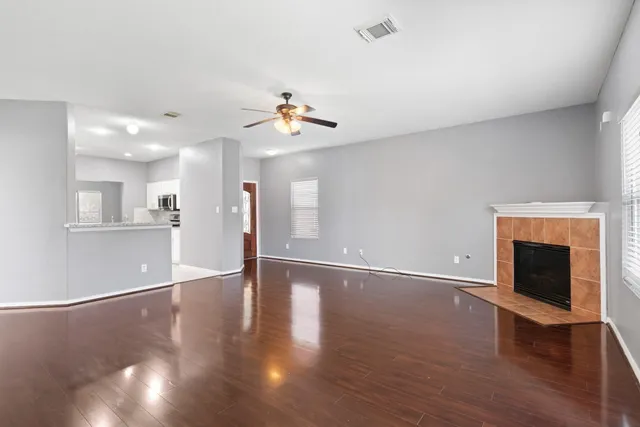 a view of an empty room with wooden floor and a fireplace