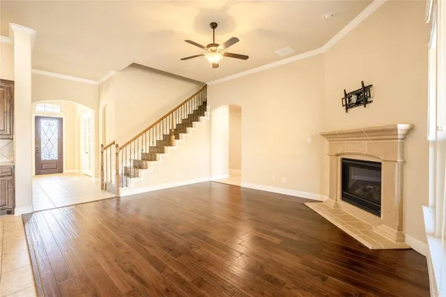 a view of an empty room with wooden floor and a fireplace