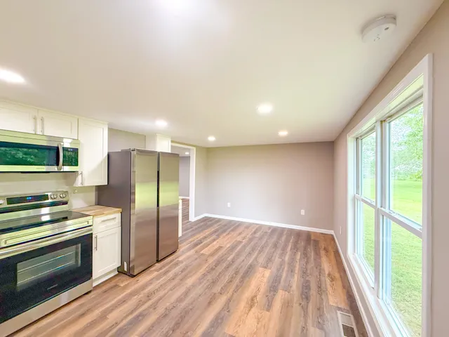 a view of kitchen with stainless steel appliances wooden floor and window