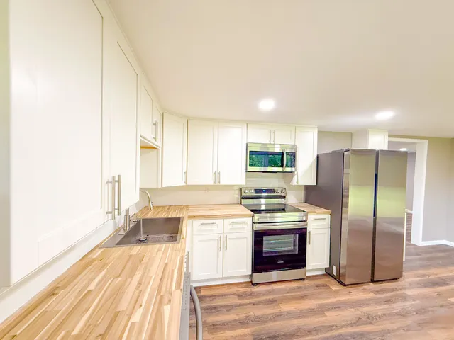 a kitchen with stainless steel appliances a stove top oven a sink and a refrigerator