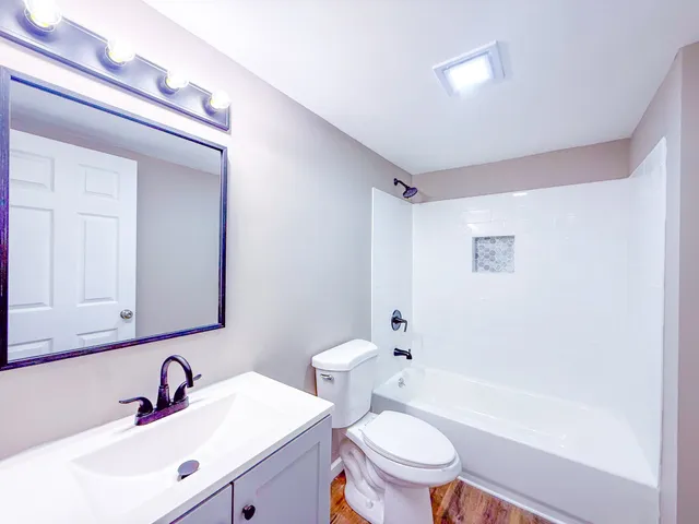 a bathroom with a bathtub shower sink vanity mirror and toilet