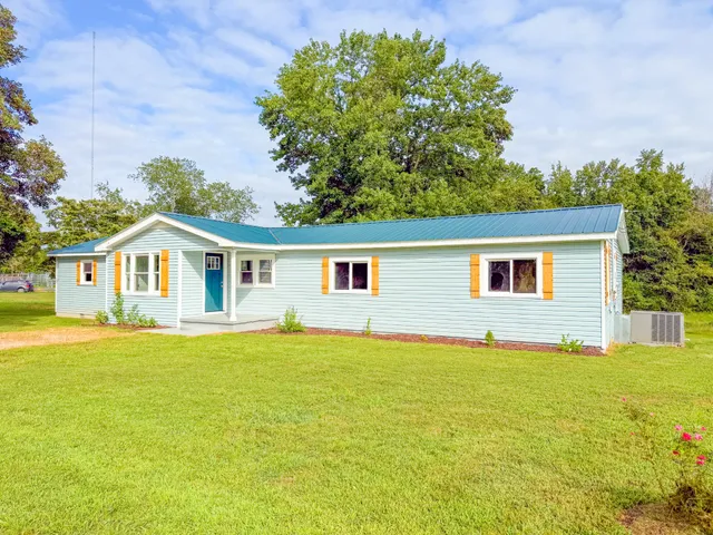 a front view of house with yard and trees in the background