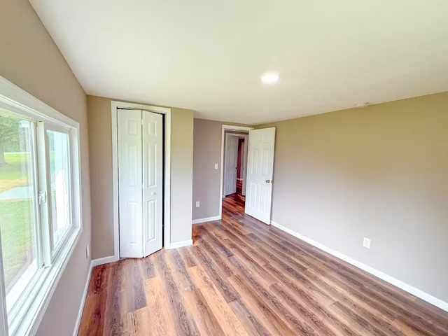 a view of a big room with wooden floor and windows