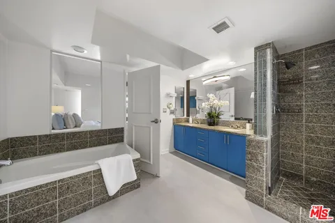a bathroom with a granite countertop sink a large mirror and a shower