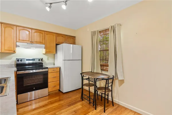 a kitchen with granite countertop a refrigerator stove and wooden floor