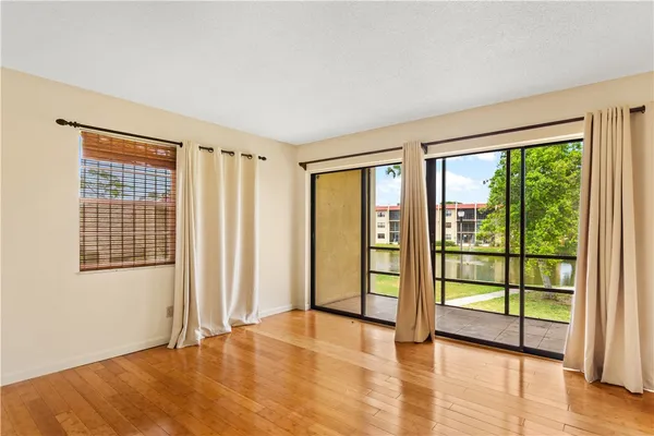 a view of an empty room with wooden floor and windows