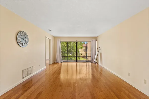 a view of an empty room with wooden floor and a window