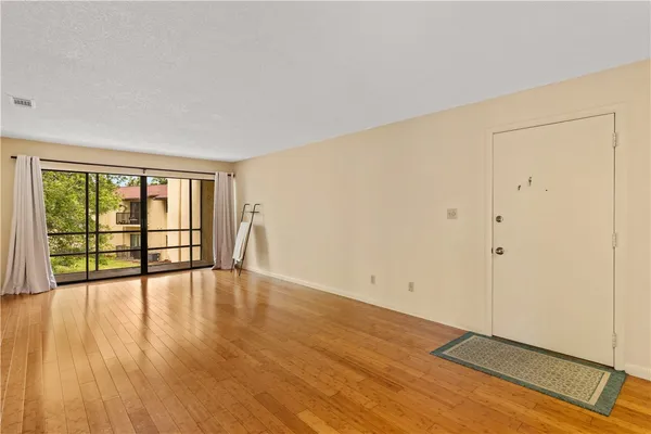 a view of an empty room with wooden floor and a window
