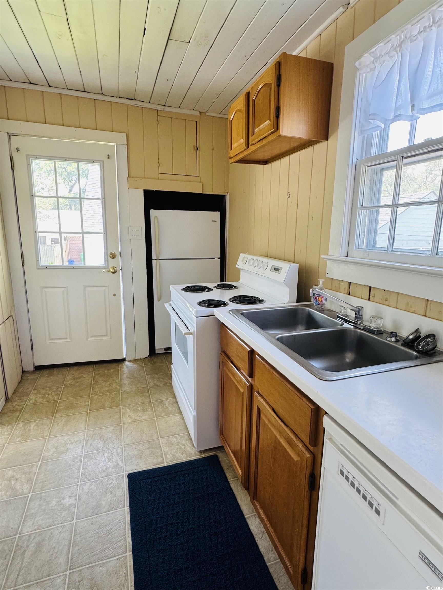 104 East Bay Street Georgetown, SC 29440 - Photo 32 of 40 Kitchen featuring white appliances, light countertops, wood walls, and brown cabinetry