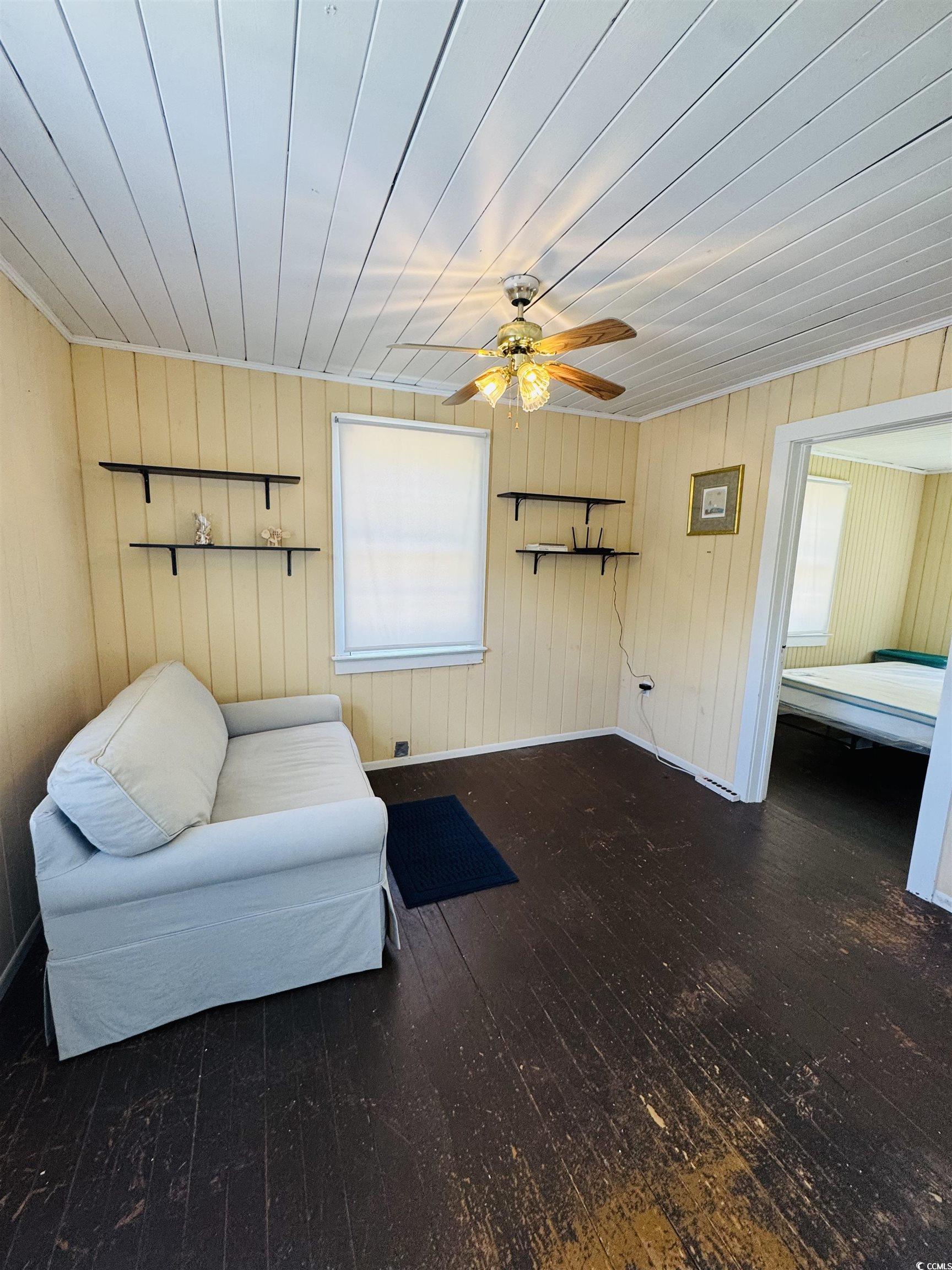 104 East Bay Street Georgetown, SC 29440 - Photo 34 of 40 Sitting room featuring hardwood / wood-style flooring, wooden walls, and a ceiling fan- Apartment
