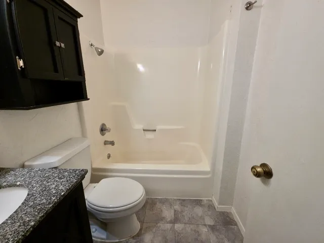 an empty room with a chandelier fan and windows