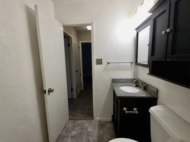 a bathroom with a granite countertop toilet and a shower