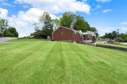 a view of a house with a big yard potted plants and a large tree