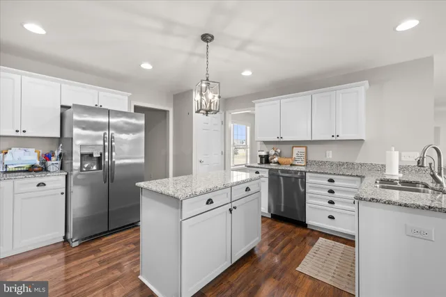 a open kitchen with stainless steel appliances granite countertop a stove oven a sink dishwasher and a dining table with wooden floor