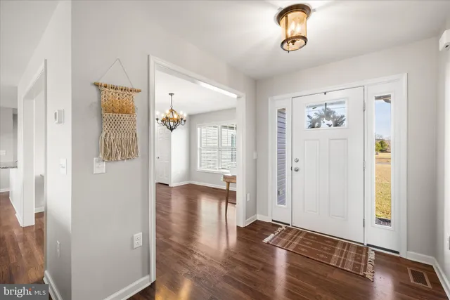 a dining room with wooden floor a chandelier a wooden table and chairs