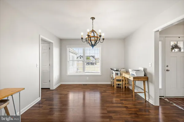 a dining room with wooden floor a chandelier a wooden table and chairs