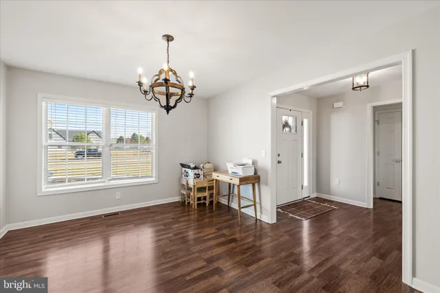 a view of a kitchen with a table wooden floor and a refrigerator