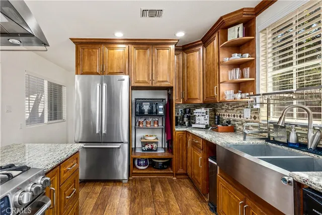 a kitchen with granite countertop a refrigerator a sink dishwasher stove and wooden cabinets