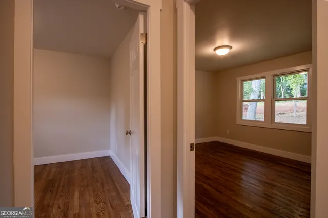 a view of hallway with window and wooden floor