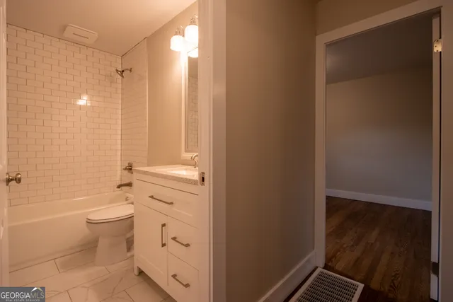a bathroom with a granite countertop sink a toilet and shower