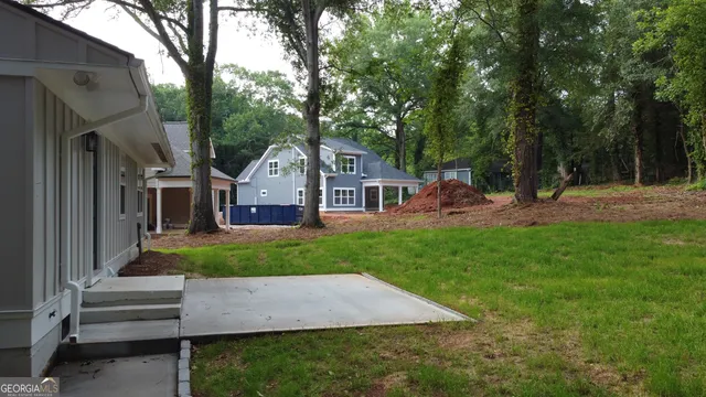 a view of a house with a big yard potted plants and large tree